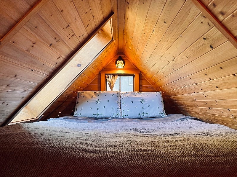 The sleeping loft with a queen size mattress, a window that opens, and a skylight with a pull down shade.