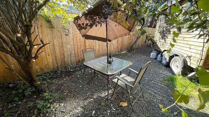 Outdoor table with chairs and umbrella in a hidden nook of the yard.