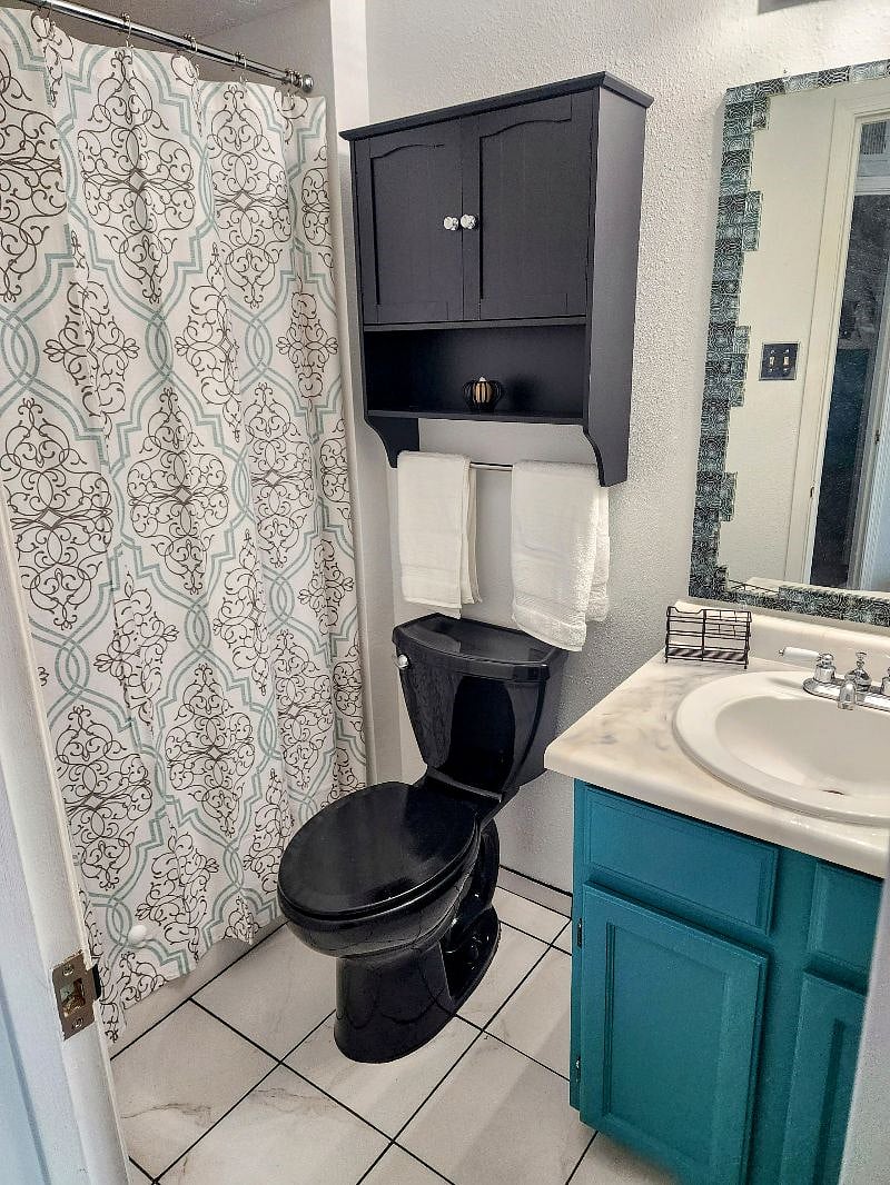 En-suite bathroom. Shower, over-the-toilet storage, medicine cabinet, under-the-sink storage, and hooks on the door for towels/robes.