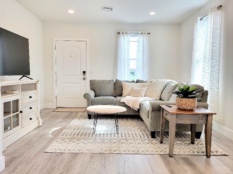 Comfortable and tastefully furnished living room with dimmable lighting, TV and blinds.