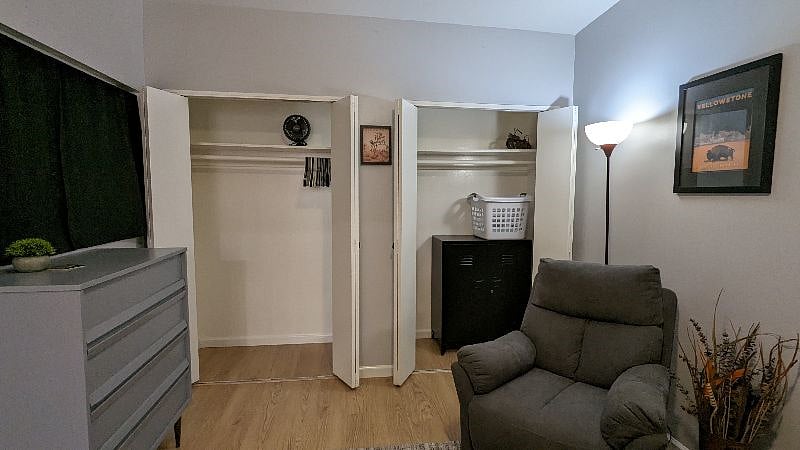 bedroom with closet doors open and la-z-boy recliner.
Fan and laundry basket available for use.
Black storage cabinet is owner's.