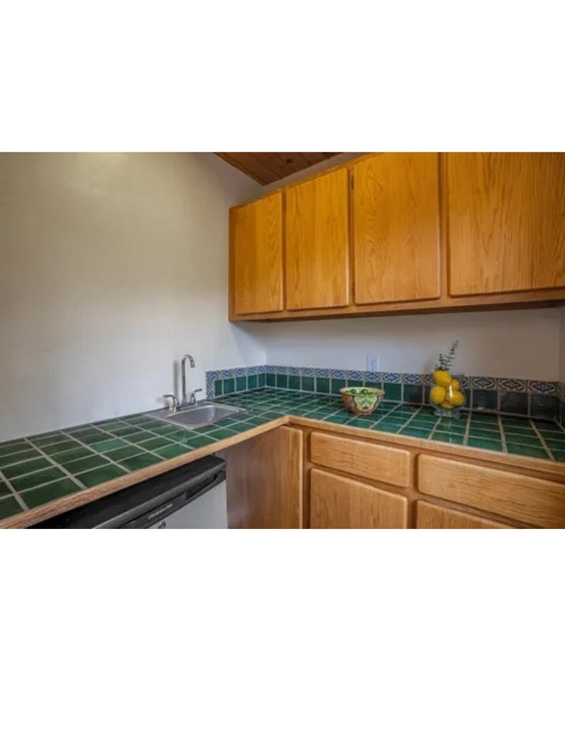 Small kitchen area with sink, microwave, and refrigerator.