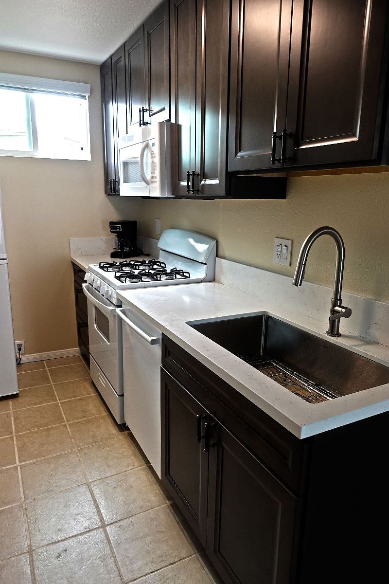 Full kitchen featuring large sink, dishwasher, and range/oven