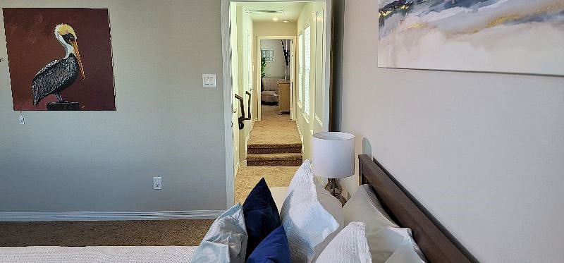 View from secondary upstairs bedroom down hallway leading to primary bedroom.