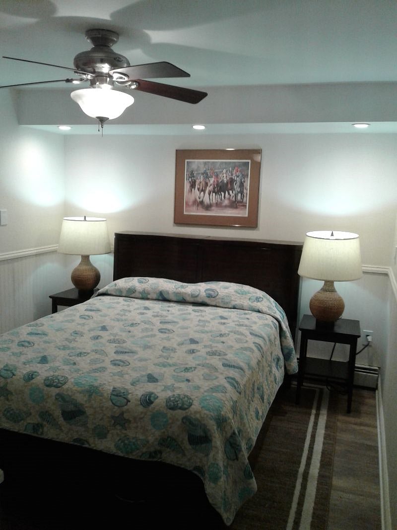 Guest bedroom with queen size bed. Bed stands have USB ports. Ceiling fan.
