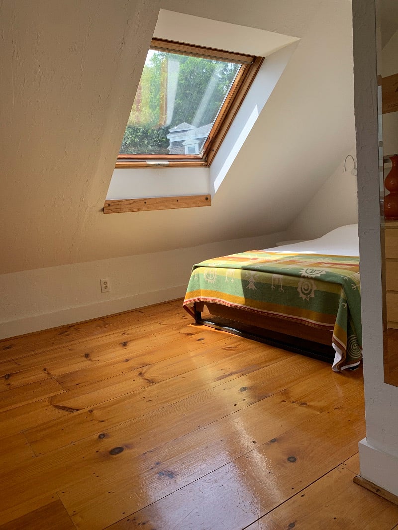 Third-floor bedroom with skylight seen from work area. A wall bordered by two open doorways on right.