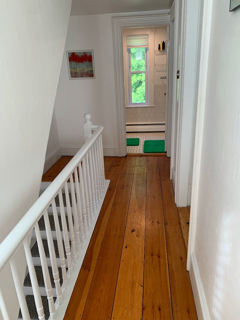 View from second-floor hallway toward full bathroom. Two bedrooms on right.