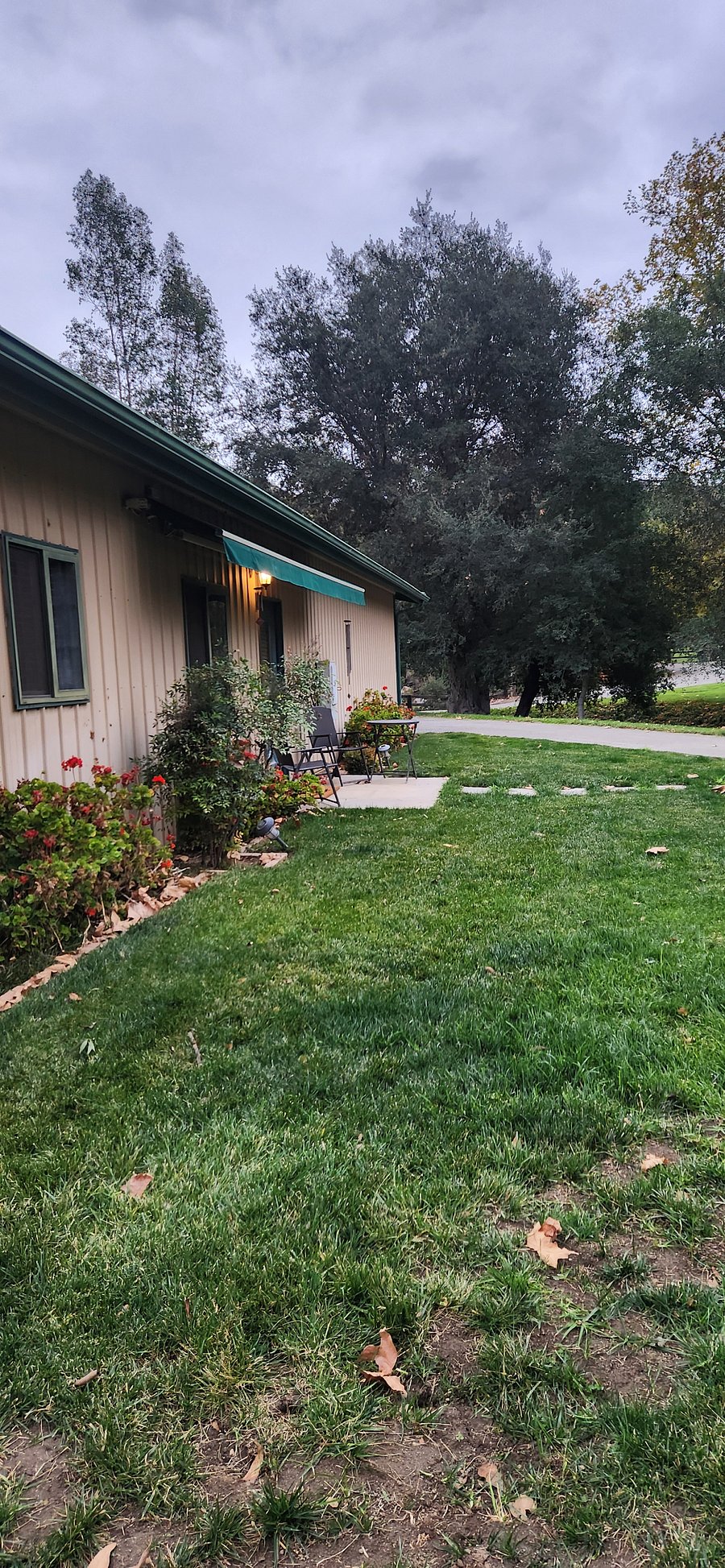 Outside view of the unit, showing retractable awning, bistro set and front lawn. Parking for your vehicle is around the corner.