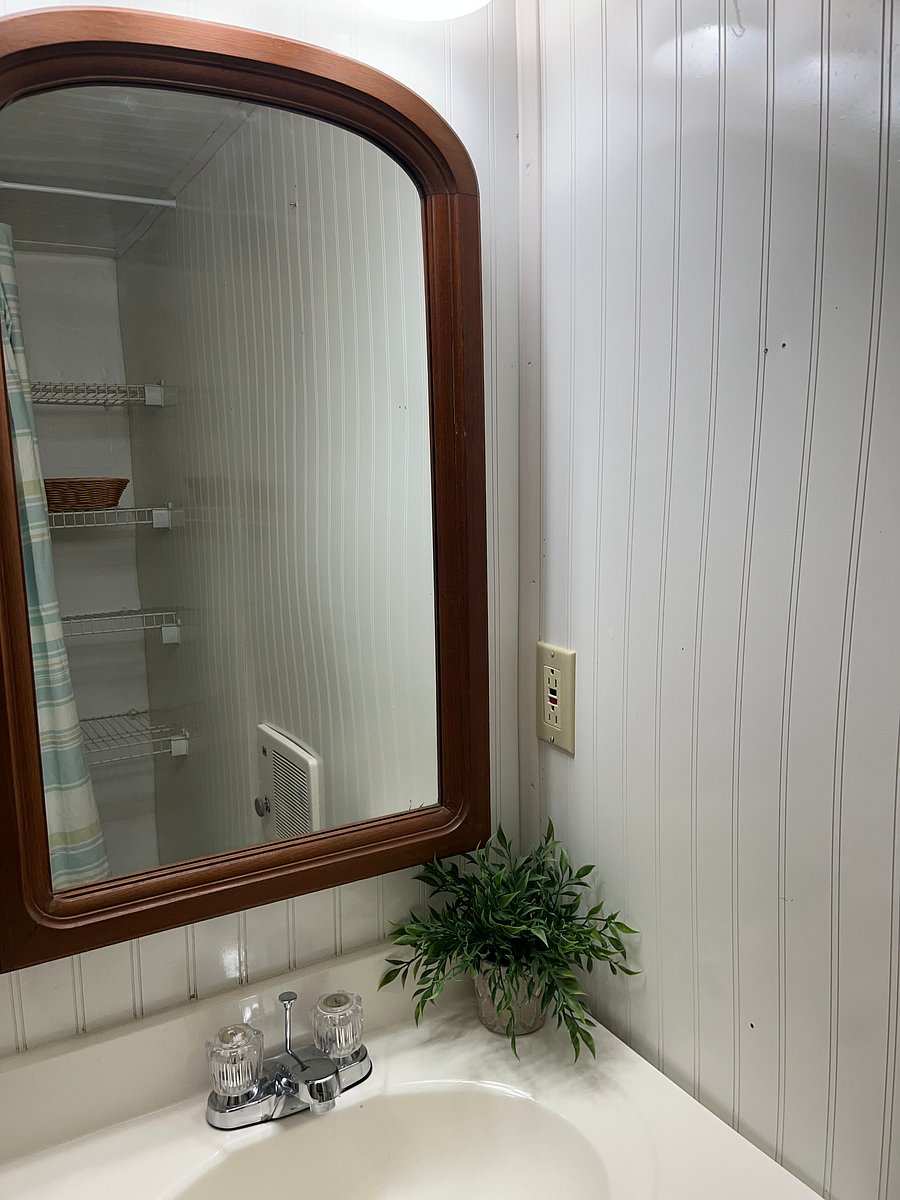 Storage in bathroom, as seen in mirror, located opposite of vanity and next to shower
