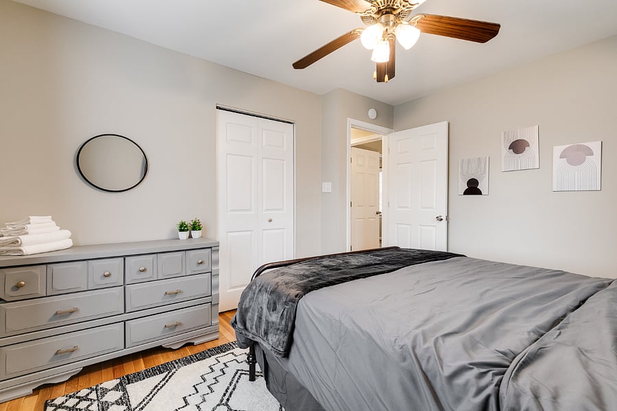 Large guest room providing ample space with boasts a queen size hybrid mattress, blackout curtains, and ceiling fan.