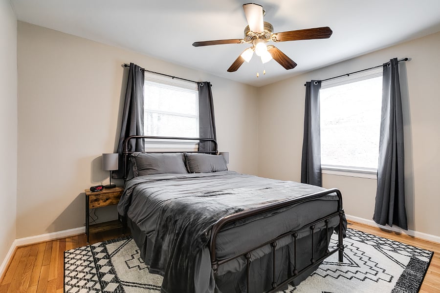 Large guest room providing ample space with boasts a queen size hybrid mattress, blackout curtains, and ceiling fan.