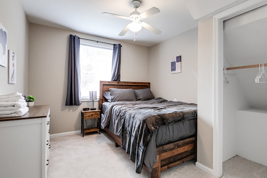 Ground level bedroom featuring comfortable queen size hybrid mattrass, blackout curtains and ceiling fan.