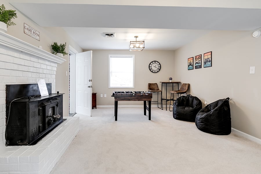 Large downstairs game room with ample space along with a 10-in-1 table game (foosball, air hocky, ping pong, pool, etc.) tons of old school video game and board games, puzzles, 55" UHD TV and sleeper sofa.
