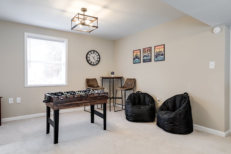 Large downstairs game room with ample space along with a 10-in-1 table game (foosball, air hocky, ping pong, pool, etc.) tons of old school video game and board games, puzzles, 55" UHD TV and sleeper sofa.
