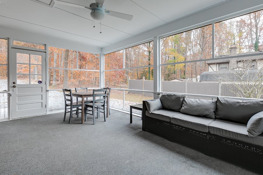 Enormous screen porch with couch, ceiling fan, HD TV and dining table.