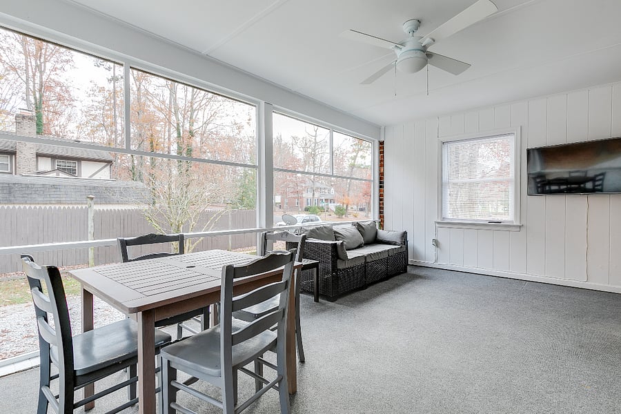 Enormous screen porch with couch, ceiling fan, HD TV and dining table.
