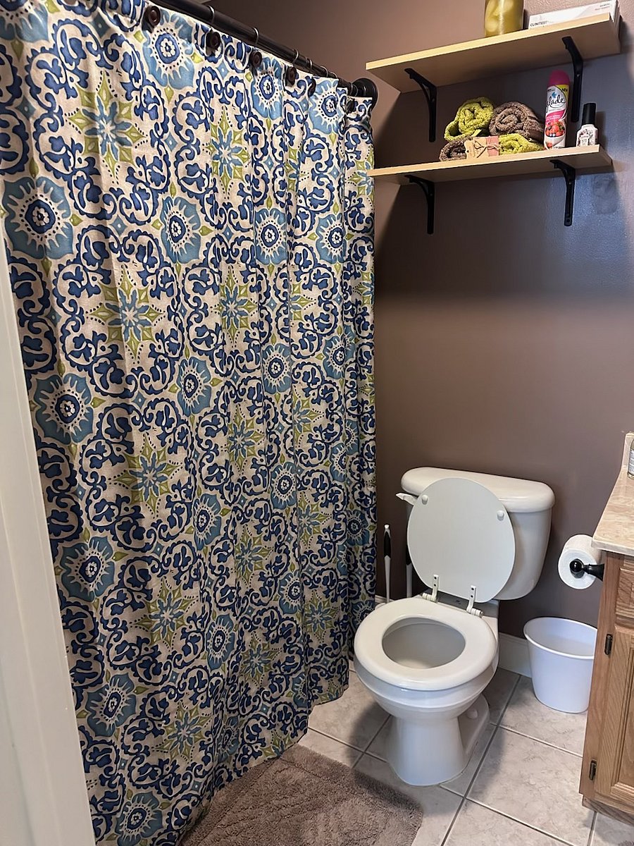 Main guest bathroom off living room hallway with full size shower/tub combination and hand held shower fixture