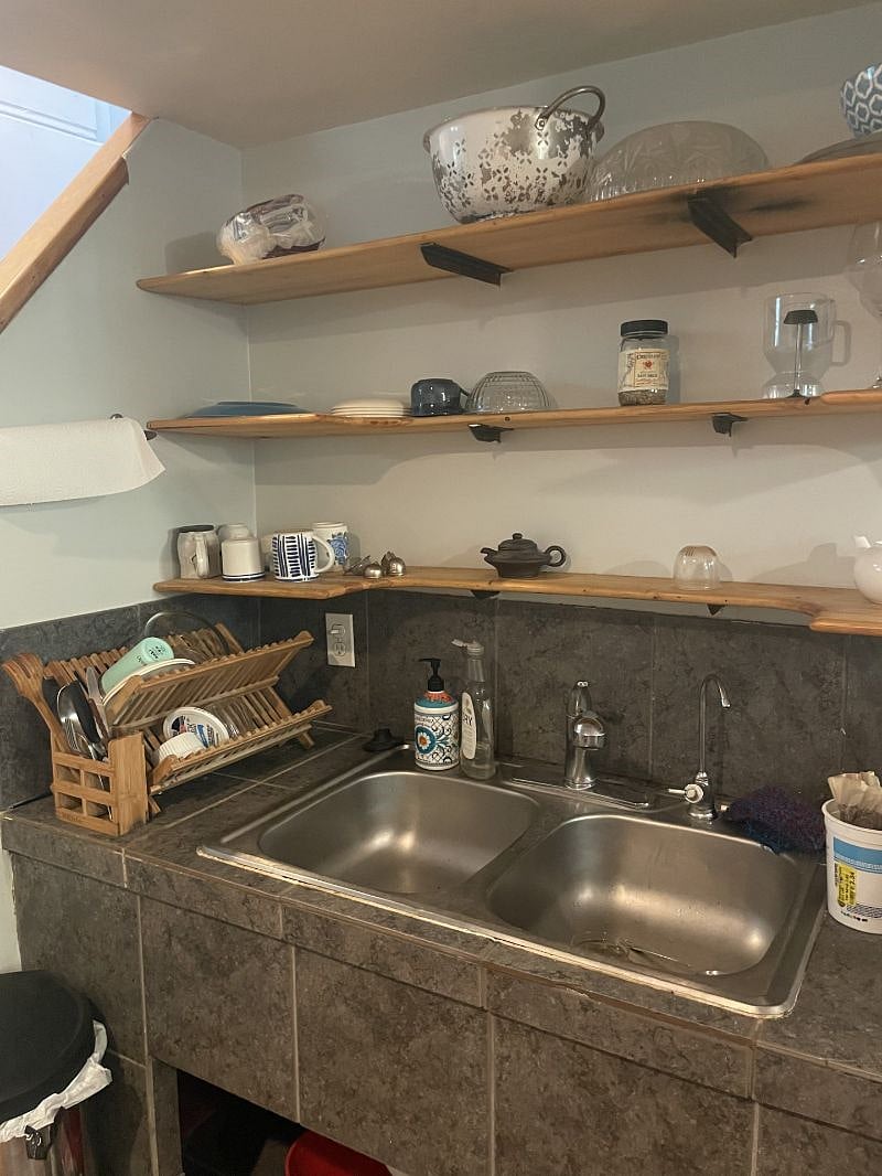Downstairs garden apartment kitchen with starter dishes and cleaning supplies.