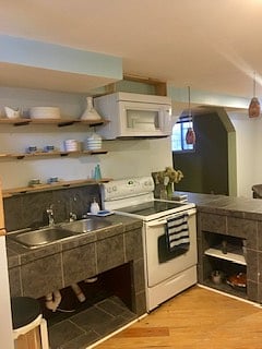 Full kitchen with shelving, built in microwave, breakfast bar, and full fridge.