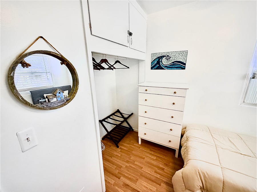Spare bedroom with open closet and 5 drawer dresser. 