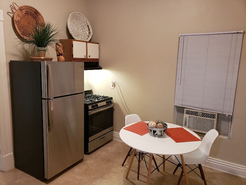 Dining table, refrigerator, gas stove, window A/C unit
