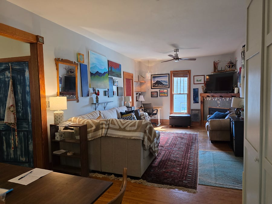 Living room with large couch, sit/stand desk workspace, Smart TV, gas fireplace, and tons of storage space in white closets.