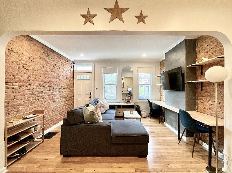 Living room with mounted television, custom-built work from home desk, and storage for shoes/keys.
