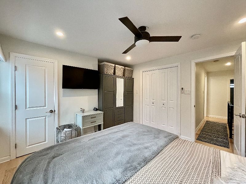 Main bedroom with armoire, mounted television, shelving storage closet, and full closet