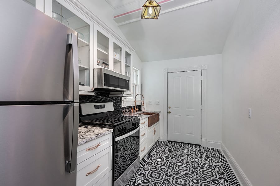 High end galley kitchen w/ copper fixtures and granite countertops, gas stove/oven