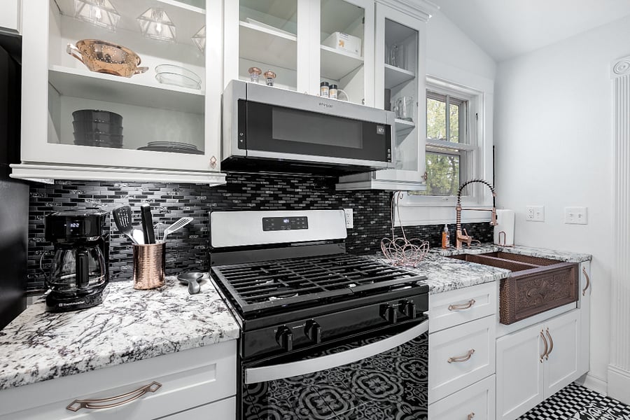 High end galley kitchen w/ copper fixtures and granite countertops, gas stove/oven