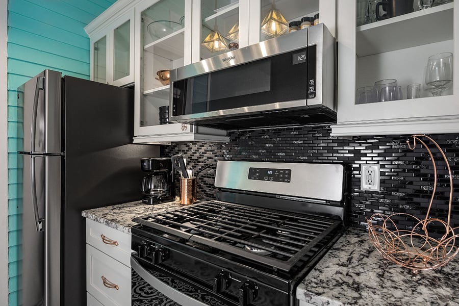 High end galley kitchen w/ copper fixtures and granite countertops, gas stove/oven