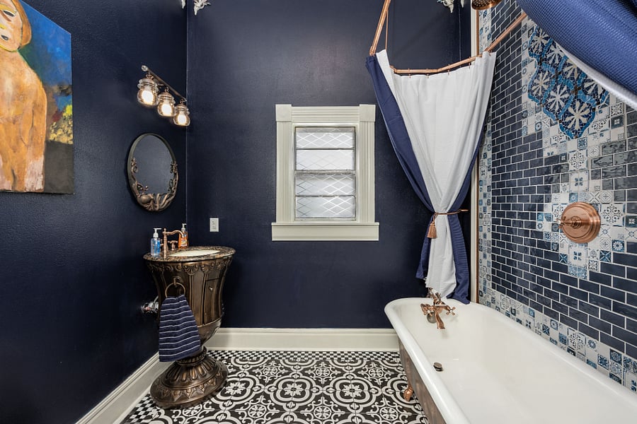 Luxurious bathroom with restored clawfoot tub, copper fixtures, and Moroccan Mosaic tile shower wall w/ rain can shower head and separate tub faucet and handheld wand.