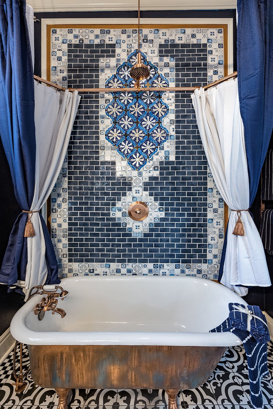 Luxurious bathroom with restored clawfoot tub, copper fixtures, and Moroccan Mosaic tile shower wall w/ rain can shower head and separate tub faucet and handheld wand.