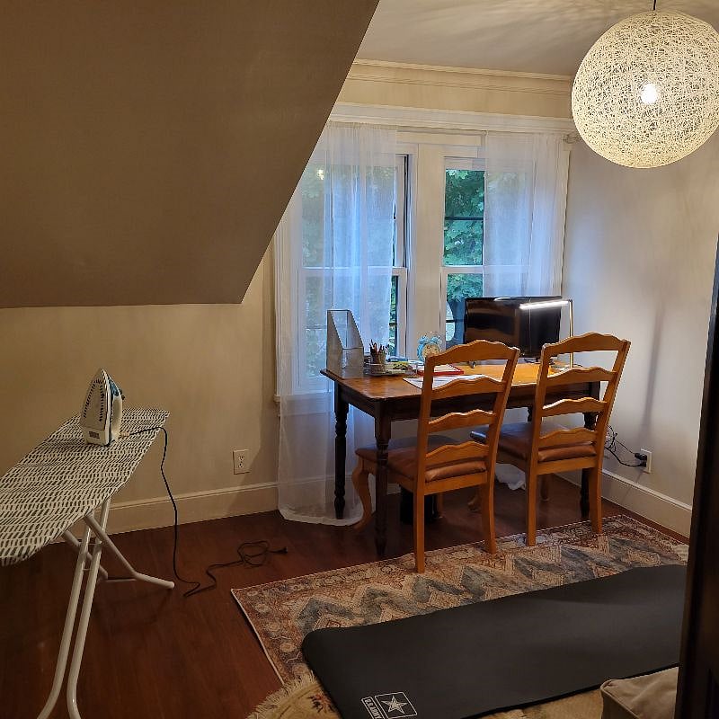 Office includes a des two chairs, an ironing board a yoga mat.