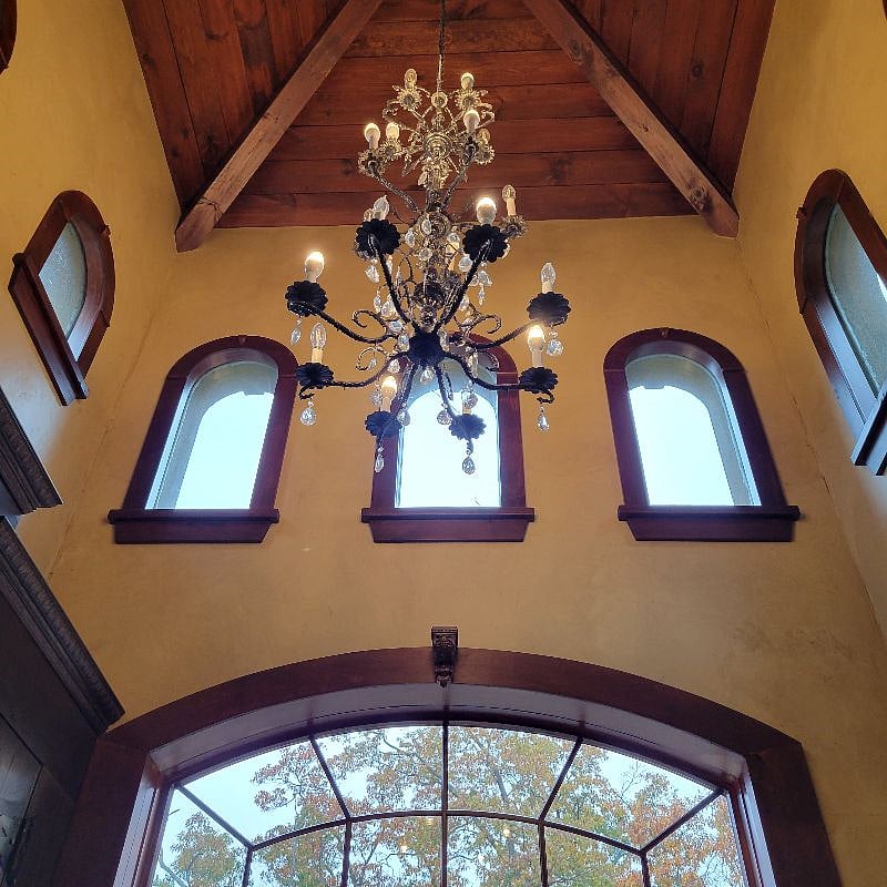 Another view of the mud room. A chandelier and windows a bench part of the dcor.