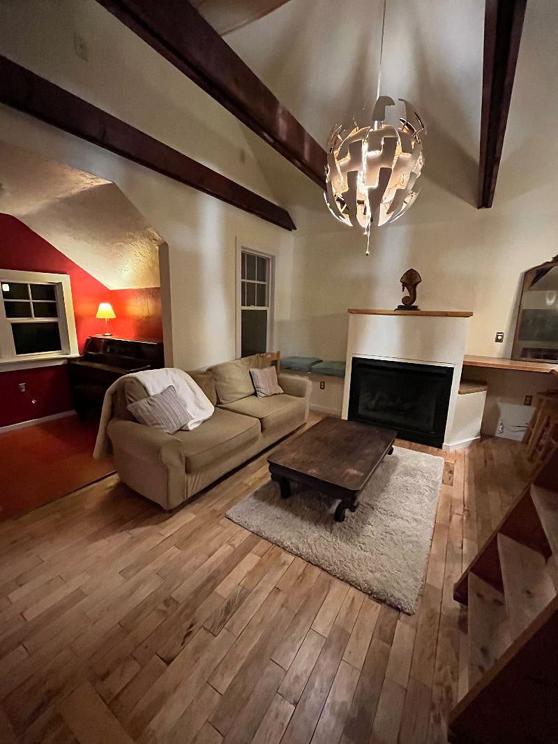 Living room has a couch and two chairs. Open format with kitchen. Out of tune piano too.