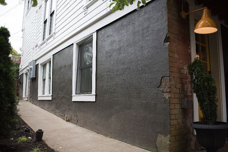 Walk down a path into the backyard where you will find the apartment's private brick patio and yellow front door