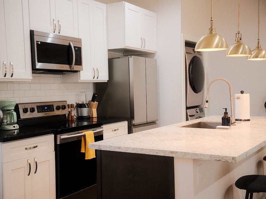 Chef's kitchen with large island, electric stove, oven, french door fridge, microwave, and dishwasher. Full size washer & dryer