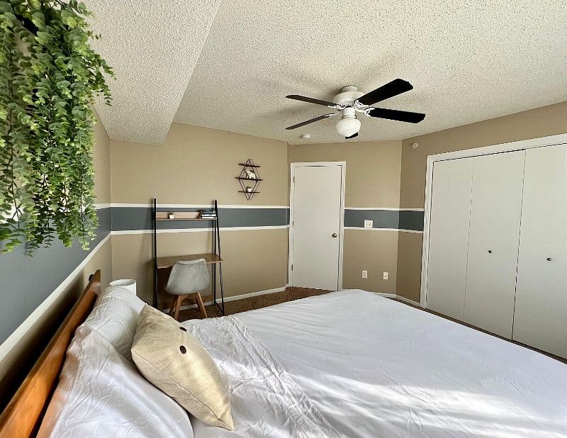 Bedroom 1 with queen-size bed, mirror, small desk, and nightstand.