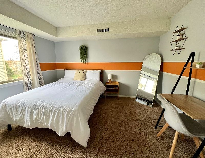 Bedroom 2 with queen-size bed, mirror, small desk, and nightstand.