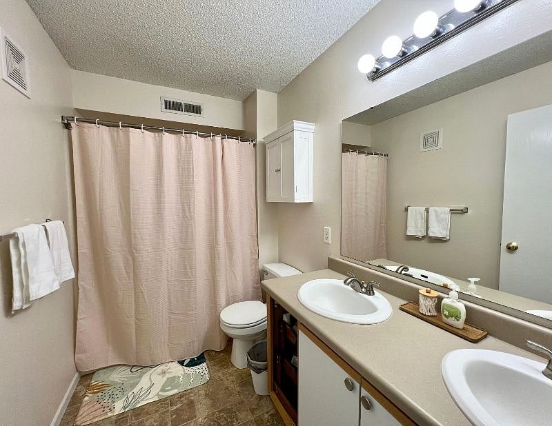 Shower/tub combo bathroom equipped with starter toiletries and double vanity.