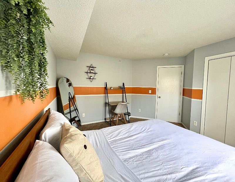 Bedroom 2 with queen-size bed, mirror, small desk, and nightstand.