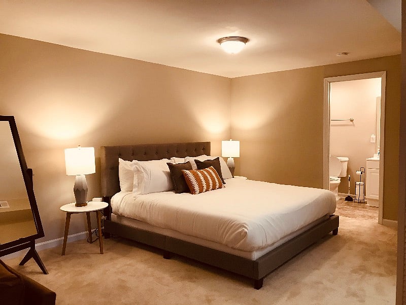 Comfy king-sized memory foam bed in private basement studio with a full-length mirror, two side tables with lamps.
