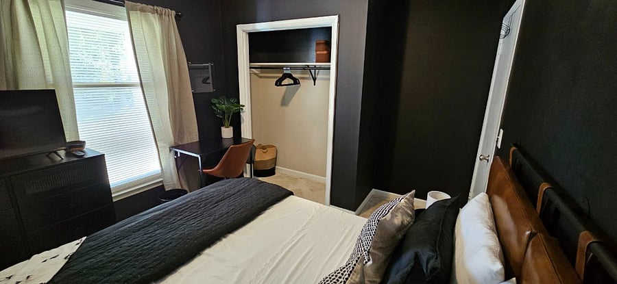 First bedroom with Queen-sized mattress, spacious closet, a desk, a dresser, room-darkening/blackout curtains, and a Roku flatscreen TV.