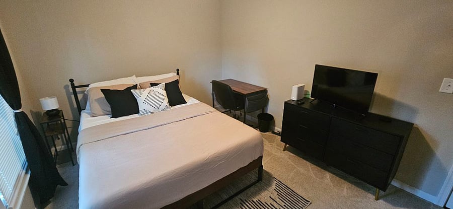 Second bedroom with Queen-sized mattress, spacious closet, a desk, a dresser, room-darkening/blackout curtains, and a Roku flatscreen TV.