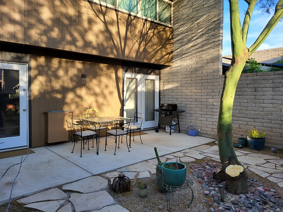 Serene shaded back patio with seating and grill