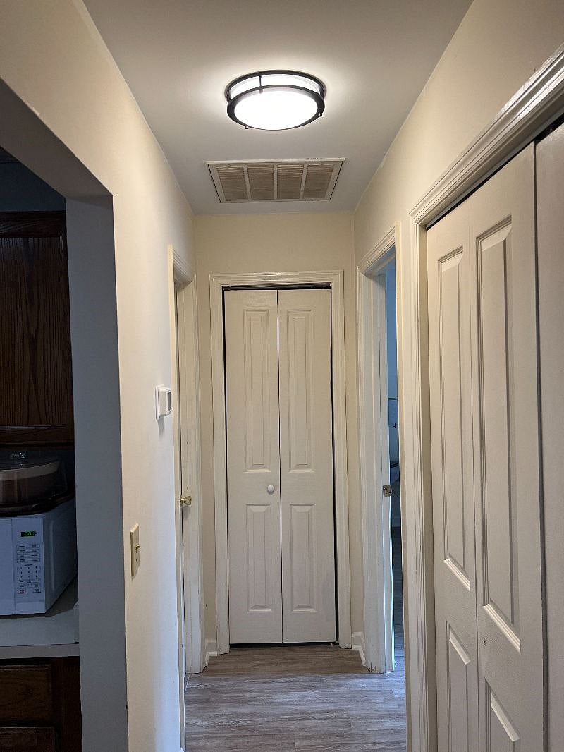 hallway leading to private spaces, laundry in cabinets on right-side.