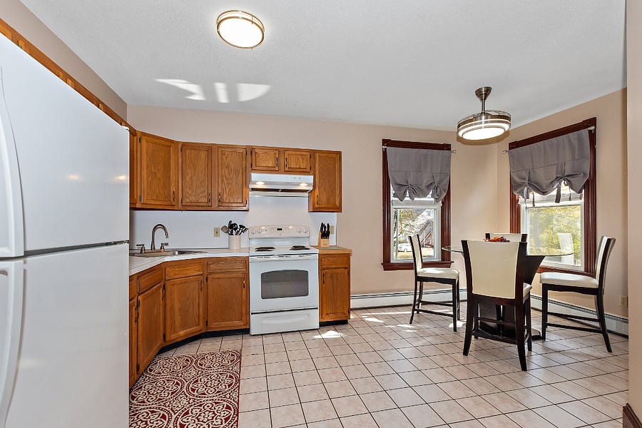 Kitchen features a microwave, Kitchen Aid stand mixer, dinnerware, pots and pans, coffee maker, toaster, spices. Ceiling fan over glass top table.