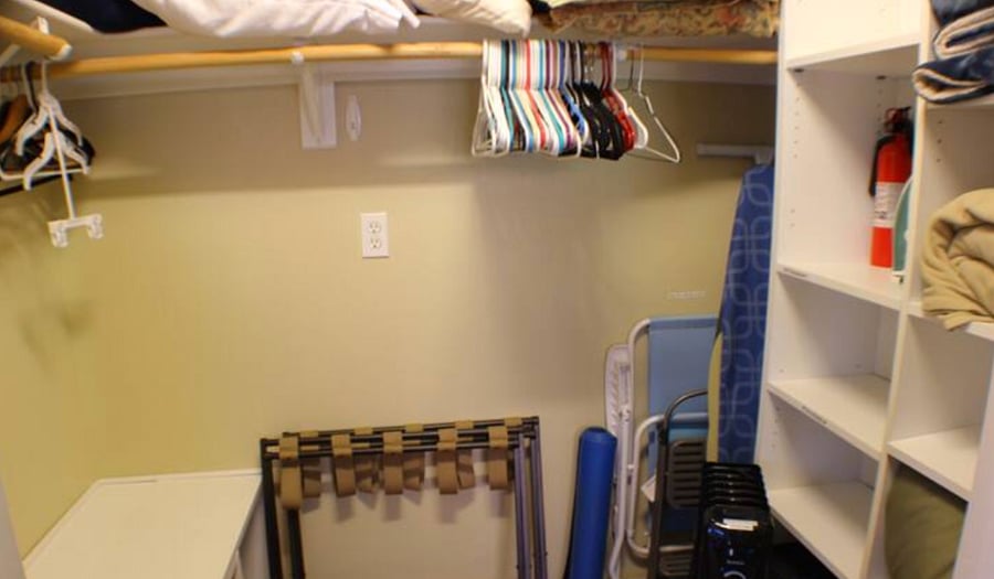 Walk-in Closet with extra bedding, yoga mat, luggage racks, iron and ironing board, and robes and flip flops for the sauna