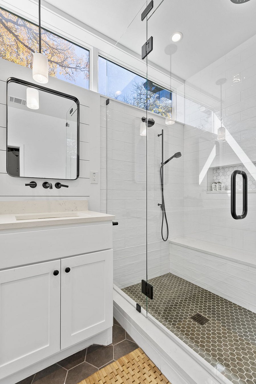 Spacious walk-in shower with three shower heads and built-in vanity to right of shower
